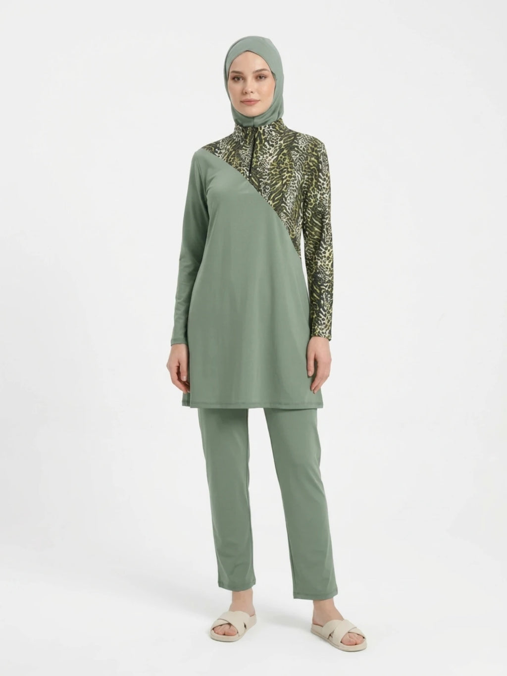 Adaçayı yeşili ve leopar desenli asimetrik detaylı tam kapalı tesettür mayo; uzun kollu fermuarlı tunik, boru paça pantolon ve uyumlu boneden oluşan üçlü set.